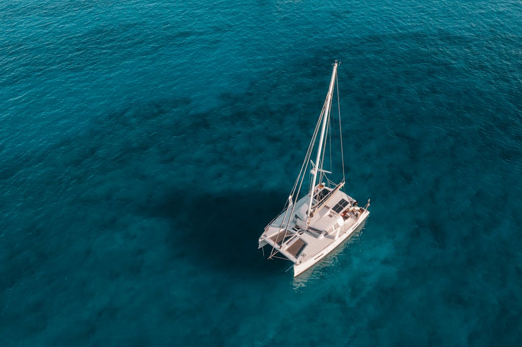 A serene aerial shot of a catamaran sailing on crystal blue waters, perfect for travel and marine themes.