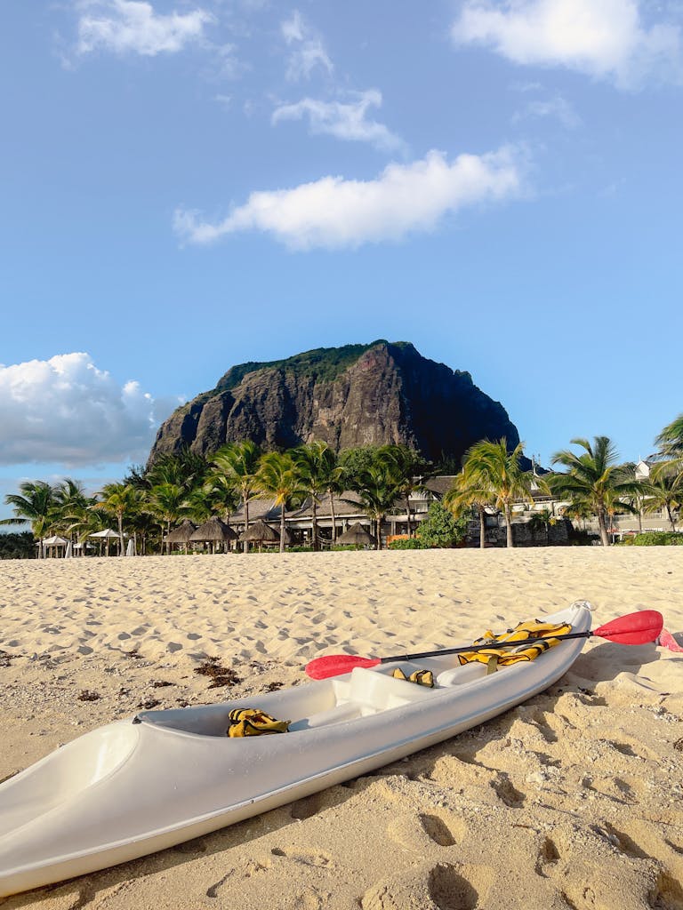 Serene beach with a canoe, palm trees, and the iconic Le Morne Brabant mountain in Mauritius.